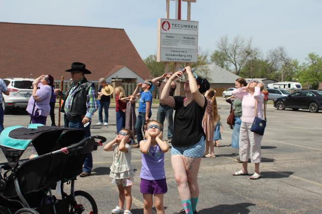 River Lucas, 3, and Mavis Lucas, 5, hold their eclipse glasses on as their mom, Taylor Rounds, tries to take a picture of the total solar eclipse with her phone during the Tecumseh Public Library Eclipse Viewing Party, held at the Tecumseh Pentecostal Church of God parking lot on April 8. Countywide & Sun/Natasha Dunagan