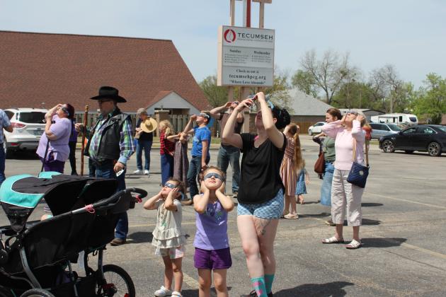 River Lucas, 3, and Mavis Lucas, 5, hold their eclipse glasses on as their mom, Taylor Rounds, tries to take a picture of the total solar eclipse with her phone during the Tecumseh Public Library Eclipse Viewing Party, held at the Tecumseh Pentecostal Church of God parking lot on April 8. Countywide &amp; Sun/Natasha Dunagan
