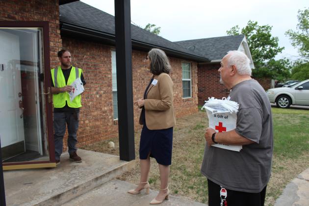 Julie McCormick talks with Shawnee resident Justin Cote after handing him a resource bag, as Red Cross disaster responder Ray Schachner listens, during the United Way of Pottawatomie County Longterm Recovery Group Tornado Outreach on April 15. During the outreach, 23 volunteers knocked on 407 doors to share the bags of resource and disaster preparedness information. Countywide &amp; Sun/Natasha Dunagan