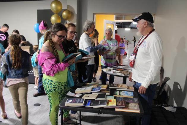 Members of the YMCA Bible Study group, including Tony Barnes, far right, Ben Williams, and Patsy Barnes, tend their booth where they gave away religious books donated by their members during the YMCA Grand Reopening Party, April 6. The Bible Study group began meeting for Lent, and has continued meeting weekly for 10 years. Countywide &amp; Sun/Natasha Dunagan
