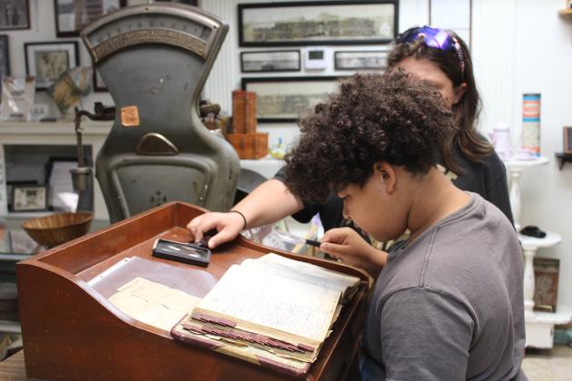Fifth-graders Elijah Sumo and Koby McInturff look through records from the Pottawatomie County Jail.