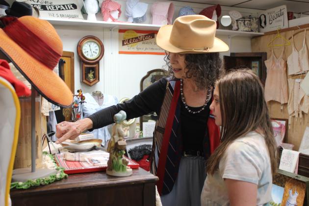 Tecumseh Historical Society Museum volunteer Ruth Beasley shows a picture of Louisa Stanley to fifth-grader Sophia Purcell during the annual tours on May 2. Stanley is the grandmother of another volunteer, Arthenia Haney, and her hat and gloves are also on display. Beasley was wearing her father-in-law's hat and a vest made from her father's ties. About seven classes visited the museum at 114 S. Broadway in Tecumseh. Countywide &amp; Sun/Natasha Dunagan
