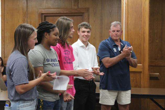 During the Shawnee Board of Education May 14 meeting, Track Coach Jaylin Stapleton, Avery Holmes, Ayden Ringwald, Keifer Landes, and Assistant Coach Bob McNeil. applaud their accomplishments at the State Track Meet. Countywide &amp; Sun/Natasha Dunagan