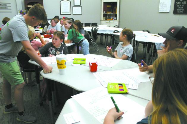 Pottawatomie County 4-H Vice President Taylor Marrs helps a member with her poster in the Leadership class during 4-H Skills Day, held at North Rock Creek High School on June 20. Other classes included making decorated cupcakes, reverse tie-dyed shirts, musical shakers, first aid kits, and a flower craft, as well as learning about animal biosecurity and podcasting. They also worked on fair projects and a service project for a veteran. Countywide &amp; Sun/Natasha Dunagan