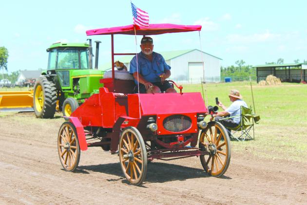 Danny Dunagan, of McLoud, and his dog Bella ride in the 1903 replica car built by his cousin during the antique tractor parade of the 25th Annual Farming Heritage Festival at Shawnee Feed Center on June 22. Dunagan has had a booth at the festival since 1998. Countywide &amp; Sun/Natasha Dunagan