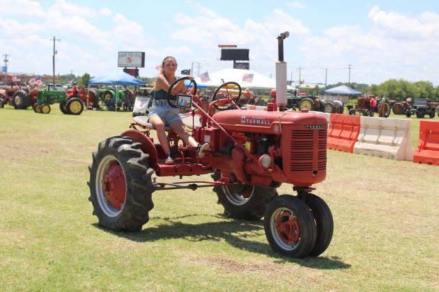 Katie Myers drives Sue Rooker’s memorial Farmall tractor for her grandfather Pete Rooker during antique tractor parade of the 25th Annual Farming Heritage Festival at Shawnee Feed Center on June 22. There were about 30 vehicles in the daily parades, June 21-22. Countywide &amp; Sun/Natasha Dunagan