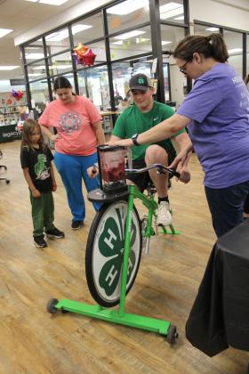 Gabe Hobbs, a North Rock Creek 4-H Club member, and 4-H Educator Kacie Jasper demonstrate the blender bike, which they were using to make smoothies, as Liam Davies, 7, of Norman, and his mom watch. 4-H was one of about 12 booths at the Shawnee Library's Blast-off to Learning event on May 30. Countywide &amp; Sun/Natasha Dunagan