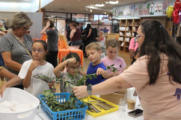 Children select materials to add to their plastic bottle bug hotels, assisted by Shawnee Library staff member Cecilia Young, during Bugfest on June 1. In addition to crafts like this, the first-time event offered a honey tasting, story time, and OSU's Insect Adventure. Countywide &amp; Sun/Natasha Dunagan
