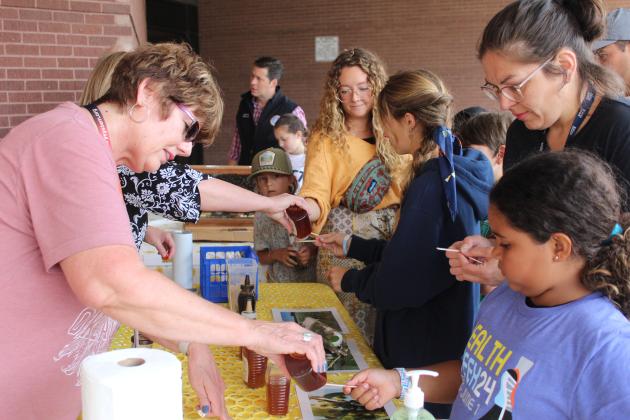 Friends of the Shawnee Library member Debbie Collins squeezes some honey onto a stick for Josslyn Springer, 8, of Shawnee, to taste during Bugfest at the library on June 1. There were about six types of honey to sample, collected by Rick Schantz of Central Oklahoma Honey near Harrah. He and his wife, Pam, also brought a section of their hive - about 300-400 bees - to view under glass. For more information, visit centraloklahomahoney.farm. In addition, Bugfest featured OSU's traveling "Insect Adventure."