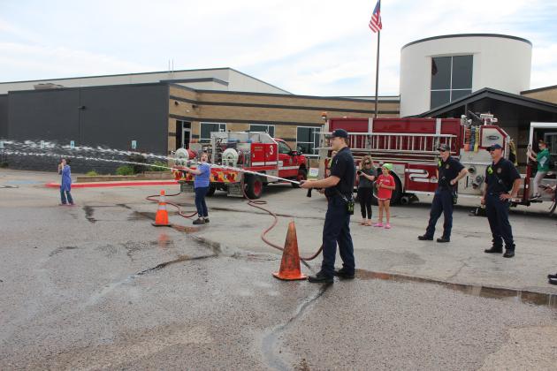 Gracie King, a 4-H Club member, competes against Shawnee Fire Department Sgt. Austin Miller in spraying a C-collar pad off a traffic cone during the Healthy Kids Day/Pups &amp; Pals event at the Shawnee YMCA on June 1. Lt. Chris Bertram and Cpl. Conner Gitthens were also on hand to give tours of the fire engine. Countywide &amp; Sun/Natasha Dunagan