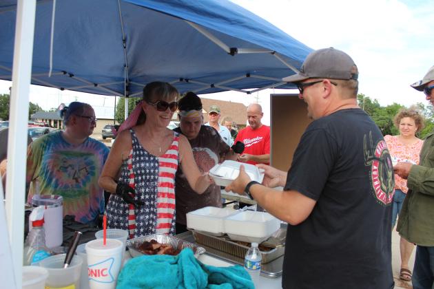 Kim Mellinger serves up an order of barbecue brisket, which was smoked and sliced by her husband Danny Mellinger during the amateur barbecue contest at the Mingle on Main Street Block Party in Tecumseh on June 20. The Mellingers offered ribs and chicken, as well, and received third place for chicken. Also shown is their daughter Shelby Mellinger and friend Kiley Sims. Countywide &amp; Sun/Natasha Dunagan