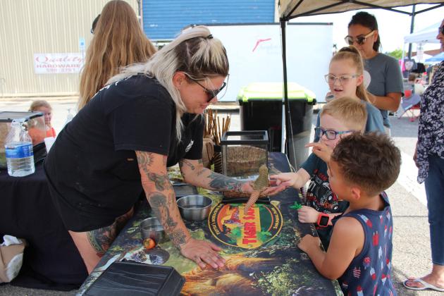 Tiger Safari Zookeeper Sarah Grunden holds a Nigerian Uromastyx lizard Jensen and Atlas, from the Experience Church, pet it, and Eliyah watches at the Tiger Safari booth during the Mingle on Main Street Block Party in Tecumseh, June 20. (The Countywide was asked to use only first names.) Countywide &amp; Sun/Natasha Dunagan