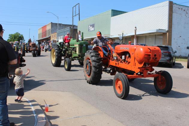 A member of the Shawnee Tractor Club waves to a young boy during the McLoud Blackberry Festival Parade on July 13. There were 75 entries in the parade. Countywide &amp; Sun/Natasha Dunagan