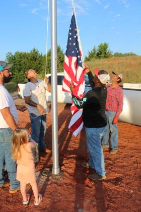 Shown clockwise, Anne Marie Thomas, 3, Ty Thomas, Shawn Edwards, Franklin Edwards and Clarence Bernard watch as the U.S. flag is hoisted for the first time on the newly installed flagpole, June 29, at Brooksville town limits. Frank Phillips, not shown, said they plan to add lights around the pole, and there will be a "Welcome to Brooksville" sign near it, as well. Countywide &amp; Sun/Natasha Dunagan