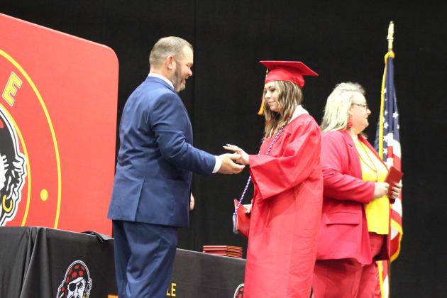 Dale Graduate Mia Hasbell gives a present to Principal Erick Muncy after receiving her diploma from School Board President Robin Wiley Greene on May 13. This year, the graduates gave tiny cowboy hats because Muncy said he was "always telling them to take their hats off in the building." Countywide &amp; Sun/Natasha Dunagan