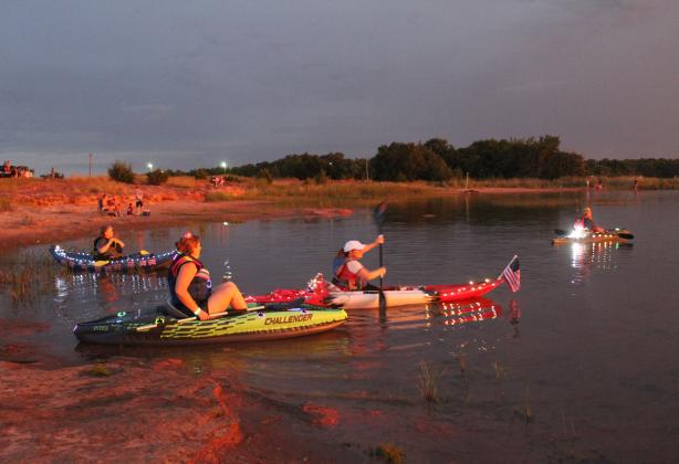 Vivi Milakovic and Denoda Martin take off from the shore of Shawnee Twin Lake #2, as Denise Manson, Martin’s mother, far left, hangs out at the bank during the Fifth Annual Pott. County Kayak Club 4th of July Glow Paddle. The event has attracted almost 70 members in the past, but rain kept the numbers to an estimated 30 to 40 this year. Countywide &amp; Sun/Natasha Dunagan