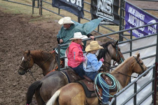 Naudia Walters, of Boley, pats Mia Manion, of Stroud, on the back after they had a rough try at team roping in the mud during the International Finals Youth Rodeo on July 7. Tom Geraldine, who works for the IFYR, holds the gate as they exit. Countywide &amp; Sun/Natasha Dunagan