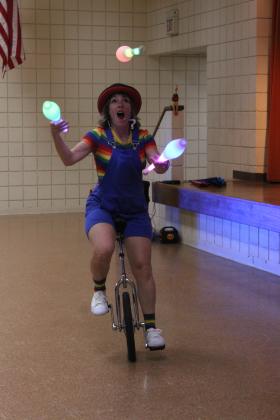 Chelsea Parks, from the Inspyral Circus, demonstrates how she can juggle pins while riding a unicycle at the Tecumseh Pioneer Library program on July 11. The theme of the children's show was "practice makes progress." The next children's program in the Summer Learning Challenge is "Cinderella Interactive - A Literary Tale" at 2 pm today (July 18) at the Tecumseh library. Countywide &amp; Sun/Natasha Dunagan