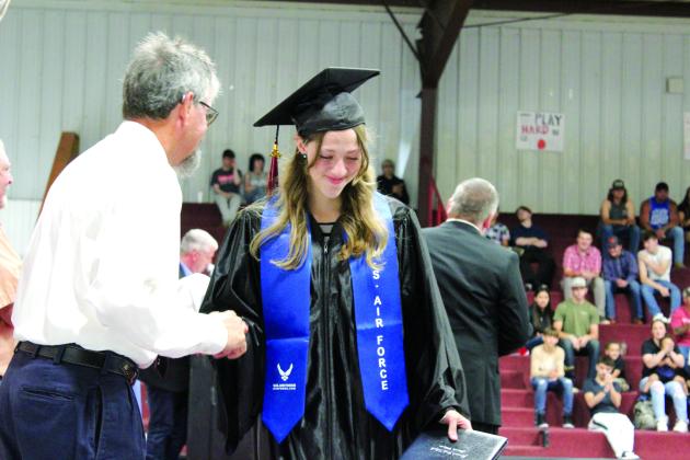 Macomb Graduate Halle Looman shakes hands with retired teacher Wayne Howard after receiving her diploma on May 4. Looman is joining the Air Force. Howard was one of two commencement speakers, along with Nathan Floyd. Countywide &amp; Sun/Natasha Dunagan
