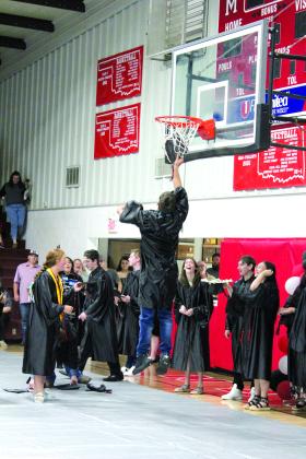 Macomb Graduate Cameron Richardson jumps up to retrieve his cap after making a basket with his toss during graduation on May 4. Countywide &amp; Sun/Natasha Dunagan