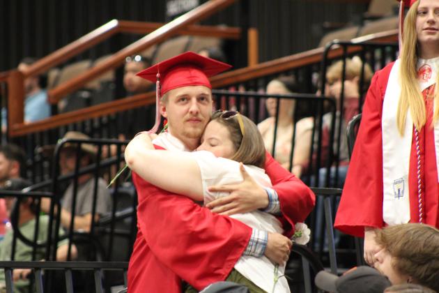 McLoud Graduate Jackson Humphrey gets a hug after giving a carnation at graduation on May 18. Countywide &amp; Sun/Natasha Dunagan