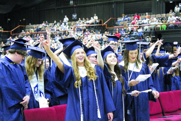 Some of the 186 Shawnee graduates make the sign of the wolf as "Hail, Shawnee High School" is sung by members of the SHS Choir. Shown, in the front row, is Bella Koepke, Holly Valentine and Kennedy Santos. Countywide &amp; Sun/Natasha Dunagan