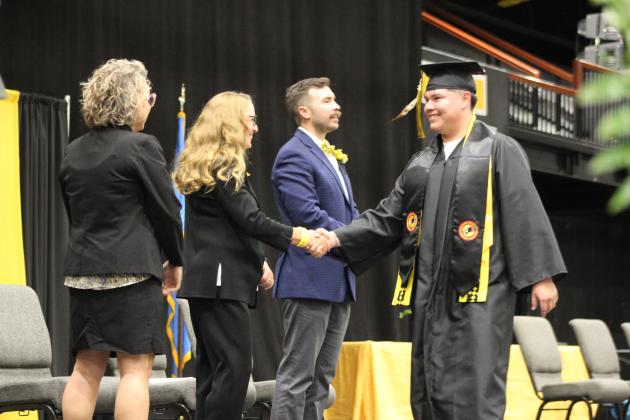 Tecumseh Graduate Braylen Walker shakes hands with School. Board Member Iva Bingham at graduation on May 21. Countywide &amp; Sun/Natasha Dunagan
