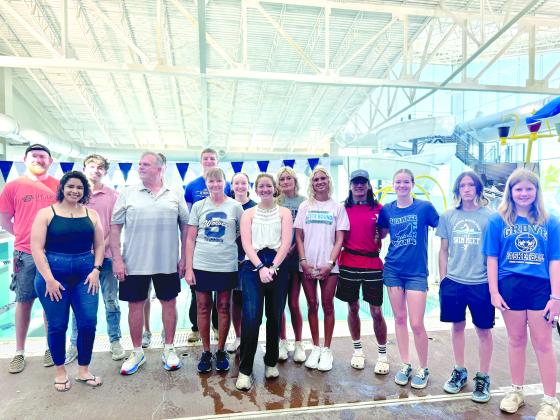 Past and present members of the Shawnee High School Swim Team pose with SHS Assistant Coach Bob McNeil, fourth from left, and SHS Head Swim Coach Valarie Colburn, sixth from left, during the Grand Reopening of the Shawnee YMCA pool on July 13. The SHS swim teams have had to use other pools to practice since the tornado on April 19, 2023, but despite that, the girls team won the state championship this year. Photo provided by Amanda Teape Johnson.