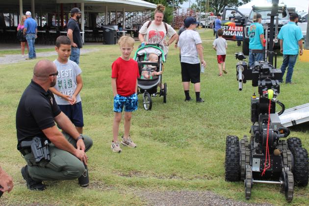 Sgt. David DeFord, of the Oklahoma County Bomb Squad, answers questions about their robot from Luke Hernandez, 7, of TX, and Jett Radtke, 6, of Shawnee at the Touch-A-Truck portion of the FireLake Fireflight Balloon Festival on Aug. 10. Countywide &amp; Sun/Natasha Dunagan