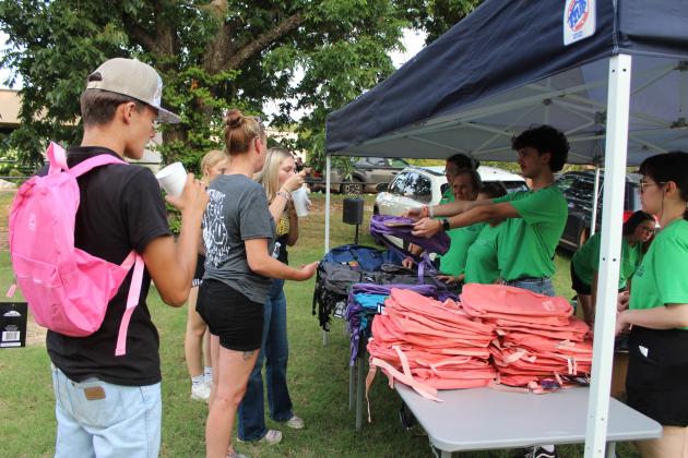 BancFirst teller Gage Haffner offers a backpack to the Turner family during the BancFirst Back to School Bash in McLoud, held at the lot just west of the bank on July 25. At their first scheduled event, BancFirst had 330 backpacks filled with school supplies available, according to Regional Marketing and Sales Manager Shannon Chandler. They also gave out free hotdogs and snow cones. In Tecumseh, the BancFirst Back to School Bash was held  on July 29, and there will be one in Shawnee today (Aug.1) at 6:30 pm