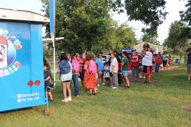 After receiving their backpacks, a long line formed for snow cones during the BancFirst Back to School Bash in McLoud, held at the lot just west of the bank on July 25. At their first scheduled event, BancFirst had 330 backpacks filled with school supplies available, according to Regional Marketing and Sales Manager Shannon Chandler.  They also gave out free hotdogs. In Tecumseh, the BancFirst Back to School Bash was held on July 29, and there will be one in Shawnee today (Aug.1) at 6:30 pm.