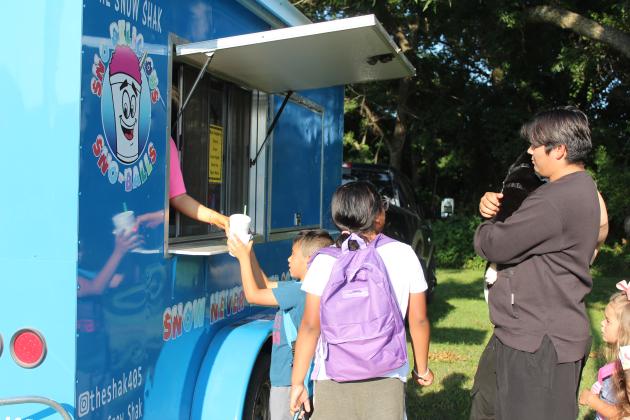 Xzavier Martinez, 8, of Shawnee, gets the beginnings of his snow cone from The Snow Shak before adding flavoring at a different station during the BancFirst Back to School Bash, held behind the Tecumseh branch on July 29. In addition to free snow cones and hotdogs, Regional Sales &amp; Marketing Coordinator Shannon Chandler said they ordered 1,008 backpacks filled with school supplies to give out at their McLoud, Tecumseh and Shawnee locations.