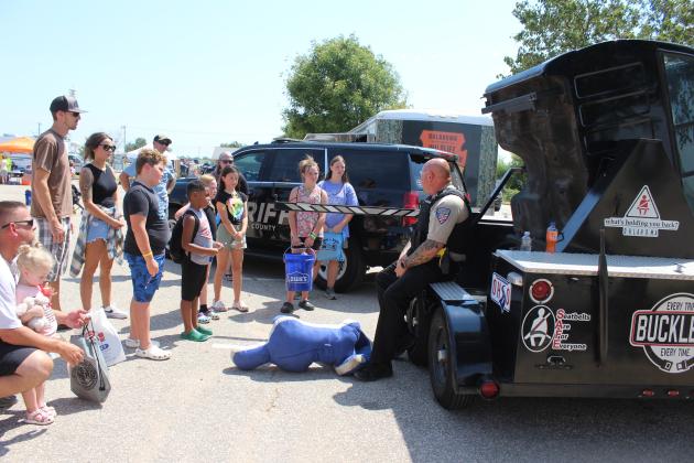 Sergeant Eric Kirby, a Traffic Safety Educator with the Oklahoma County Sheriff's Office, speaks to a crowd of children and parents about wearing seatbelts, as he sits on a roll-over simulator, at the Sixth Annual Cops n' Kids, held on Aug. 24 at the Heart of Oklahoma Expo Center. About 40 law enforcement and first responder groups and 50 organizations attracted approximately 3,000 people to this year's event. Countywide &amp; Sun/Natasha Dunagan