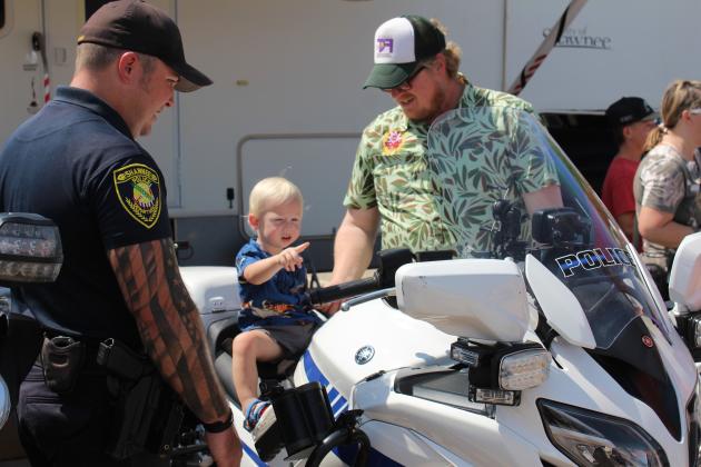 Finley Fry, 17 months, of Shawnee, sits on a Shawnee Police Department motorcycle and points at something, as Corporal Josh Soward, far left, and Fry's father, Matt Fry, keep watch at the Sixth Annual Cops n' Kids, held on Aug. 24 at the Heart of Oklahoma Expo Center. About 40 law enforcement and first responder groups and 50 organizations attracted approximately 3,000 people to this year's event. Countywide &amp; Sun/Natasha Dunagan