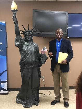 Rev. David Henry, of Shawnee, waves a flag and  poses with a miniature Statue of Liberty at his naturalization ceremony in OKC on April 30. Photo provided.