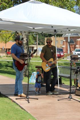 Isaac Lowe and Tyler Kupper, both with the Guitar Vault in Shawnee, perform - as Ryker Kupper, one-and-a-half years, visits his father - during the First Annual Hug-A-Thon held at Woodland Veterans Park on Aug. 3. Also with the Guitar Vault, Rodney Ackerman, Ron Ackerman, and Thatcher Guess sang, and Andy &amp; Aubrey Pope played guitar and drums, respectively, at the event. Countywide &amp; Sun/Natasha Dunagan
