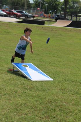 Elijah Madero, 8, of Tecumseh, tosses a beanbag in a cornhole game at the Tecumseh Pioneer Library "Party at the Park" Summer Learning Challenge celebration, held at Slick Humphrey Park on July 25. They also offered games at the pavilion, hula hoops, and a bubble machine, as well as a visit by three tortoises from Earlsboro, a Tecumseh Fire Department fire engine, and a booth from the Gateway to Prevention and Recovery (TSET) Healthy Living Program. Countywide &amp; Sun/Natasha Dunagan