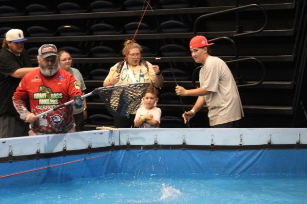Jaxxon King, of Tecumseh, far right, catches a catfish, which is scooped up by one of the Army Bass Anglers at the fishing pool during the Outdoor Network Expo at FireLake Arena on Aug. 9. Countywide &amp; Sun/Natasha Dunagan