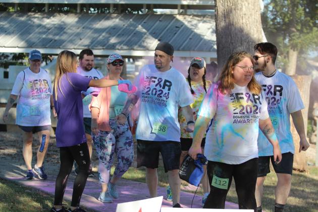 Whitney Coots, left, and Brenna Wold (hidden), both of Indian Child Welfare add some pink powder to participants' T-shirts during the House of Hope Third Annual Color Fun Run on Oct. 5 at the Citizen Potawatomi Nation Festival Grounds. There were 27 volunteers helping with the event, and an estimated 130 to 150 participants. Countywide &amp; Sun/Natasha Dunagan