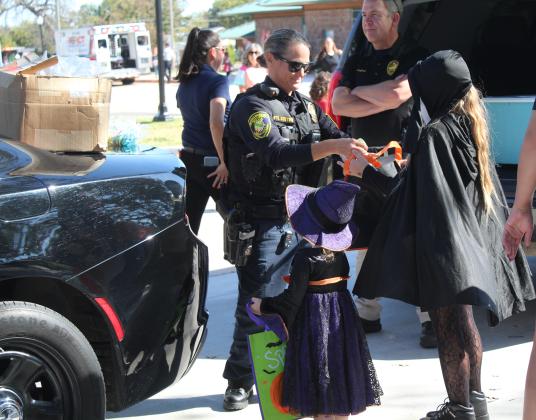 Shawnee Police Officer Kelli Cotton fills trick-or-treat bags at the Enchanted Woodland event at Woodland Veterans Park on Oct. 26. She was joined by Officers Cameron and Tucker, Corporal Vivian Lozano, Sergeant Keehn and Captain Stafford. Shawnee Fire Department also handed out treats. They included Travis Cooley, Braylee Dickerson and Brandon Don. Several organizations and businesses participated, and at least 500 children, plus their parents, attended. Countywide &amp; Sun/Natasha Dunagan