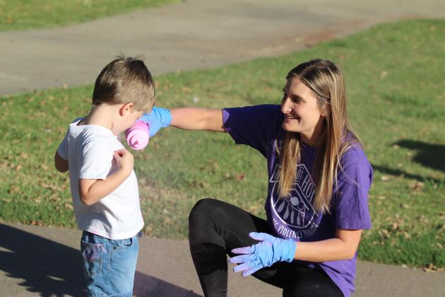 Third Annual House of Hope Color Fun Run volunteer Whitney Coots adds pink powder to Zeke Wallace, 3, of McLoud, who needed some encouragement and was then all for it.