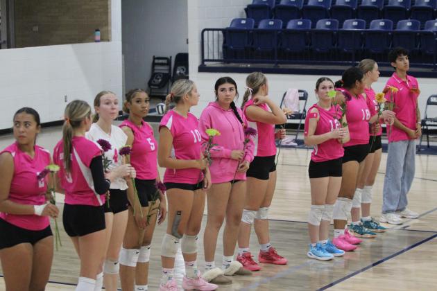 The Lady Wolves Volleyball Team looks for hands raised by cancer survivors in the audience so they may present them with flowers before the Pink Out game on Oct. 1. Countywide &amp; Sun/Natasha Dunagan