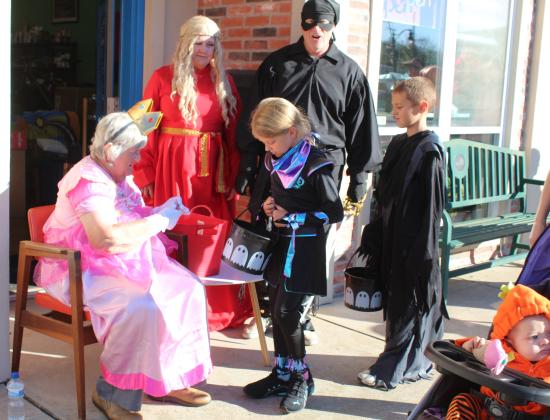 Fran Topping's mother, Alene Topping, dressed as Princess Peach from Mario Brothers, hands out candy during Tecumseh Business Trick or Treating on Oct. 31. spOKeLAHOMA Owners F. Topping and Craig MacIntyre stand watch, dressed as Princess Buttercup and Wesley from "The Princess Bride."  F. Topping said her mother has looked forward to this event every year since they moved their business to Tecumseh, since Halloween wasn't part of her own childhood. Countywide &amp; Sun/Natasha Dunagan
