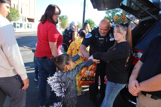 Tecumseh Police Officer Mark Botkin and Office Manager Tawana Gracy hand out candy to a little Godzilla during Tecumseh Business Trick or Treating on Oct. 31. Countywide &amp; Sun/Natasha Dunagan