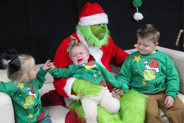 Millie Mullings, age one, is not happy sitting on the Grinch's lap, even with the support of her siblings, Kate Mullings, 3, and Koe Mullings, 5, at Grinchmas in Tecumseh on Dec. 5. Free pictures with the Grinch were offered by the Tecumseh Public Library in the City of Tecumseh Chambers, while Selfies with Santa were available on the auditorium stage. Countywide &amp; Sun/Natasha Dunagan