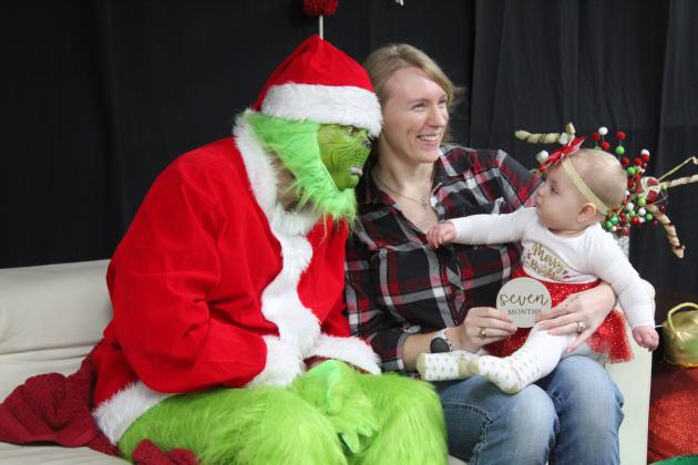 Safe on her mother, Lorin Bowie's lap, Bonni Bowie, seven months, both of Tecumseh, warms up to the Grinch for free pictures from the Tecumseh Public Library during Grinchmas and Whoville on Dec. 5. Countywide &amp; Sun/Natasha Dunagan