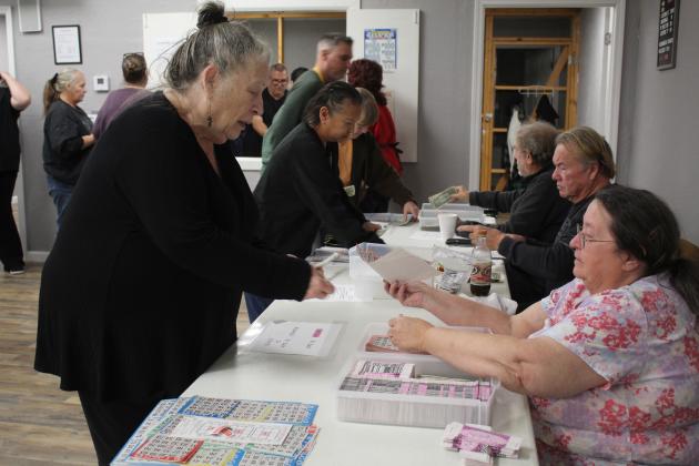 American Legion Women's Auxiliary member Jamie McCraw, right, sells bingo cards to Judy Hill, of Tecumseh, at Post 16 in Shawnee on Jan. 4. Also selling cards are Jim Vaughn and Kirk Bertolet. Countywide &amp; Sun/Natasha Dunagan