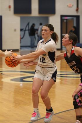 Asher's Makaylee Herrell hands off the ball to a teammate, as Macomb senior Brenna Beauchamp reaches for it, during the Jan. 28 home game. The Lady Indians won, 62-41, and the Indians shared in victory later, 66-30. Countywide &amp; Sun/Natasha Dunagan