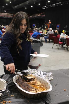 Bethel FFA student Sydne Konkler adds smoked pork to her plate at the Pottawatomie County Junior Livestock Show Pig Roast, held at FireLake Arena on Feb. 3. Countywide &amp; Sun/Natasha Dunagan