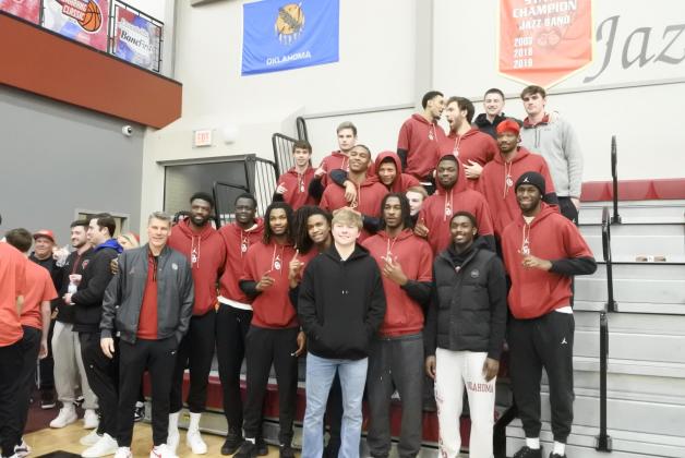 Dayton Forsythe (front, center, black jacket) is joined by OU Men's Basketball Head Coach Porter Moser and members of the OU team, Saturday, Feb. 22. During halftime of the Dale districts game, Forsythe was honored with the retirement of his number. Countywide &amp; Sun/Suzie Campbell